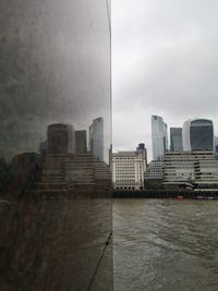 Buildings by river against sky in city