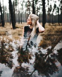 Double exposure young woman with hand in hair standing in forest