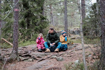 Dad having a snack with his kids whilst outside hiking