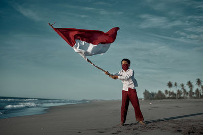 Full length of man standing on beach against sky