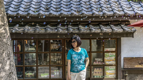 Portrait of young woman standing against building