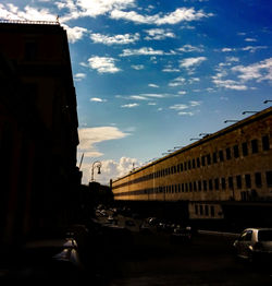 Cars on road against cloudy sky