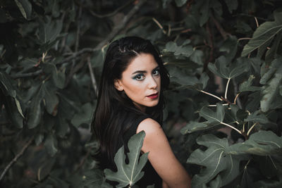 Portrait of young woman standing by plants