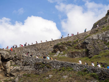 Group of people on rocks against sky in the spanish island of gaztelugatxe