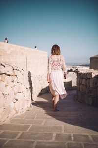 Rear view of woman walking on footpath