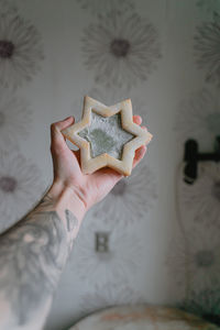 Hand with a tattoo, holding a large star made of shortcrust pastry