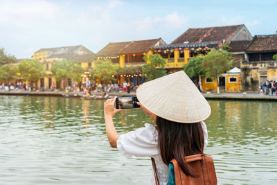 Rear view of woman standing by lake