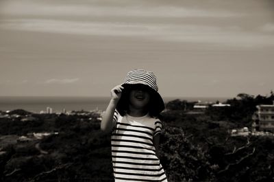 Girl wearing sun hat standing against sky