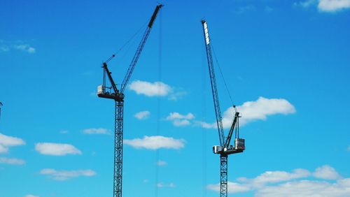 Low angle view of crane against cloudy sky