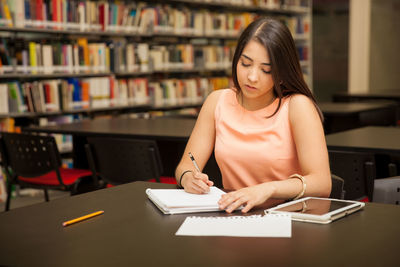 Young woman using mobile phone while sitting on table