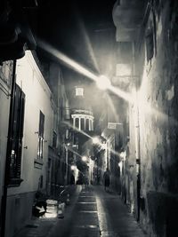 People walking on street amidst buildings in city at night