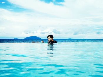 Young man in infinity pool by sea