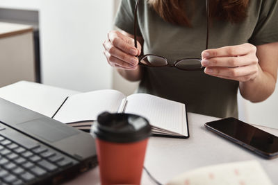 Remote work concept. freelancer work at home. woman holds glasses in hands at workplace.