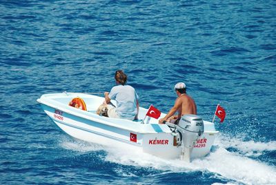 Rear view of people sitting on boat in sea