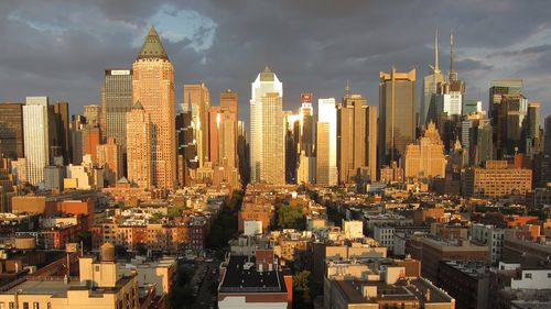 Buildings in city against cloudy sky