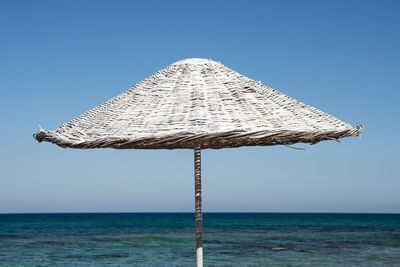 Traditional windmill on sea against clear sky