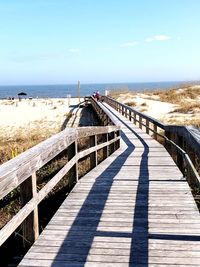 Walkway by sea against sky