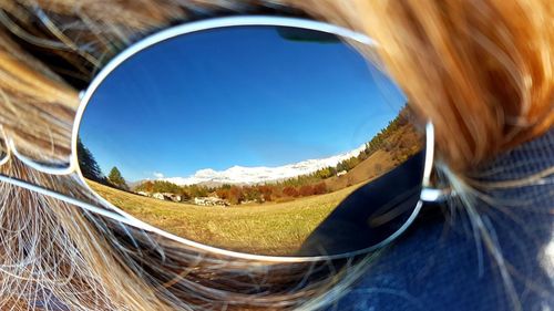 Close-up of woman wearing sunglasses against blue sky