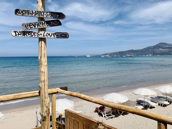 Information sign on beach against sky