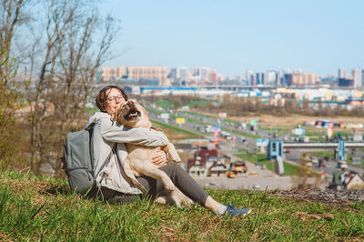 Happy girl and labrador retriever hug and laugh while sitting on a mountain. 