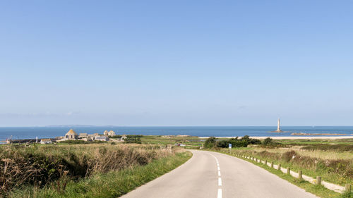 Road by sea against clear blue sky