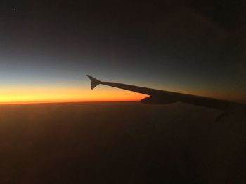 Airplane flying in sky at sunset