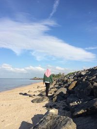 Woman on rock at beach against sky