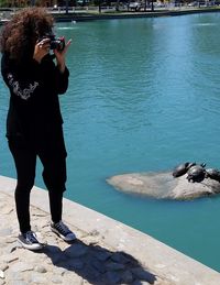 Full length of woman photographing at sea shore