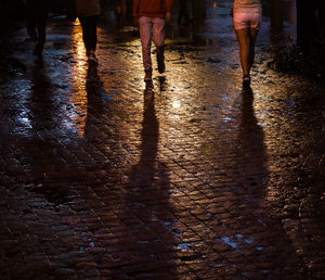 Low section of people walking on wet street