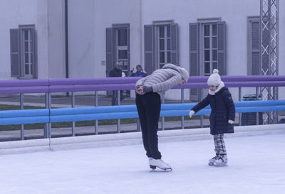 Rear view of people standing on railing during winter