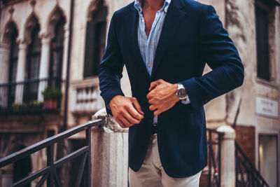 Rear view of man with umbrella standing on railing