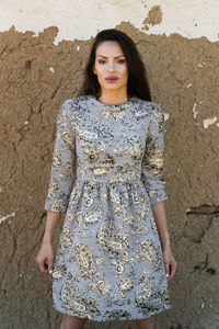 Portrait of a young woman standing against wall