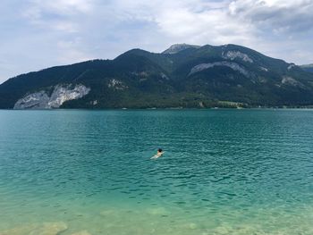 Person swimming in sea against mountains