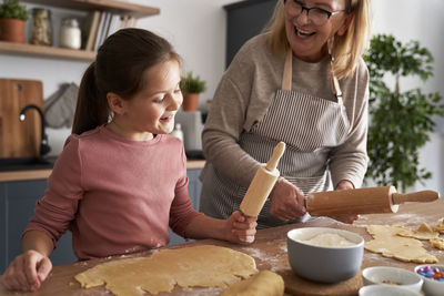 Grandma and granddaughter rolling dough