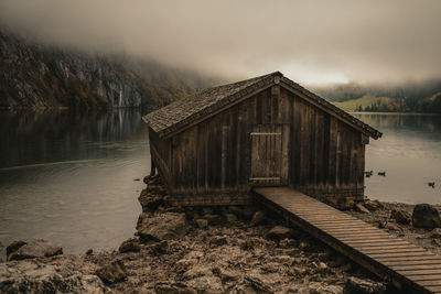 Log cabin by lake during foggy weather