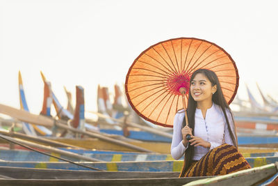 Portrait of a smiling young woman sitting against sky