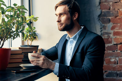 Young man looking away while sitting on wall