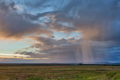 Scenic view of field against storm clouds