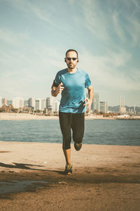 Full length of man running on sand against sea at beach