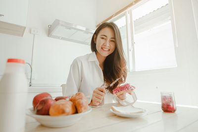 Portrait of a smiling young woman having food at home