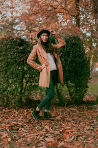 Portrait of smiling young woman standing in park during autumn