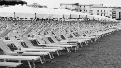 Empty chairs on beach against sky