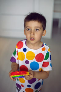Boy in a shirt with colorful circles plays with a silicone pop it toy