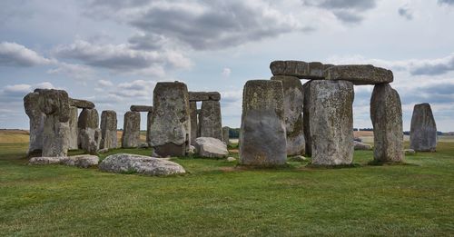 Stone structure in field against cloudy sky