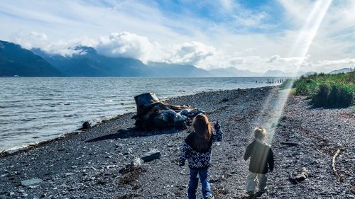 Rear view of woman on beach against sky