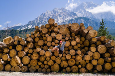 Woman sitting on the stack of the tree logs