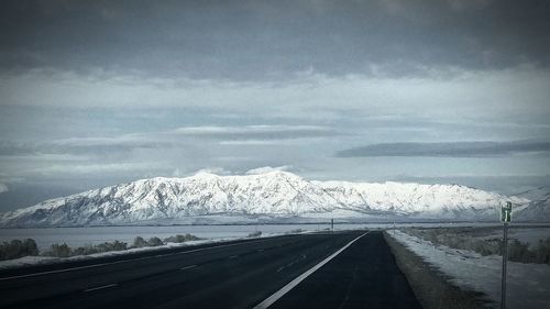 Road by snowcapped landscape against sky at night