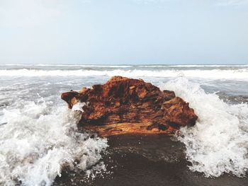 Rock formation on sea shore against clear sky