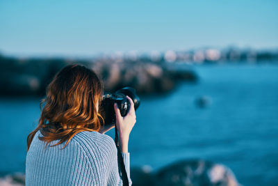 Rear view of woman photographing sea