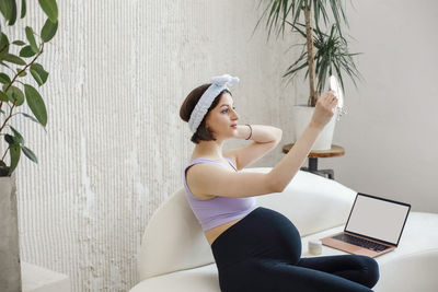 Pregnant woman looking in mirror at home